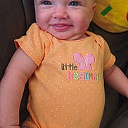 Davina joined the competition — help win amazing prizes! baby, infant, smiling, orange_onesie, cute, child, plush_toy, yellow, cushion, face, happy, portrait, expressive, indoors, person, skin, small_hand, sitting, closeup, comfort