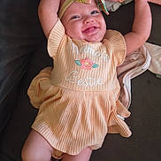 Davina is registered to the contest to win money with this photo: baby, child, smiling, dress, headband, bow, couch, happy, infant, person, cute, embroidery, fabric, pink, skin, arm, leg, indoors, relaxing, toddler