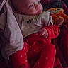 baby, bib, blanket, child, comfort, couch, cozy, face, head, indoor, infant, pajamas, person, plush, red_clothing, relaxing, seated, soft_toy, stuffed_toy, warm_lighting