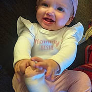 Davina is registered to the contest to win money with this photo: baby, child, infant, smiling, happy, portrait, indoor, couch, blanket, headband, bow, baby_clothing, shirt, text_on_clothing, pink_pants, sock, foot, sitting, cozy, family