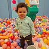 Ezra joined the competition — help win amazing prizes! toddler, child, ball_pit, colorful_balls, play_area, slide, indoor, casual_clothing, hoodie, pants, smiling, curly_hair, playful, fun, bright_colors, pastel_colors, toy, bucket, wall_art, person