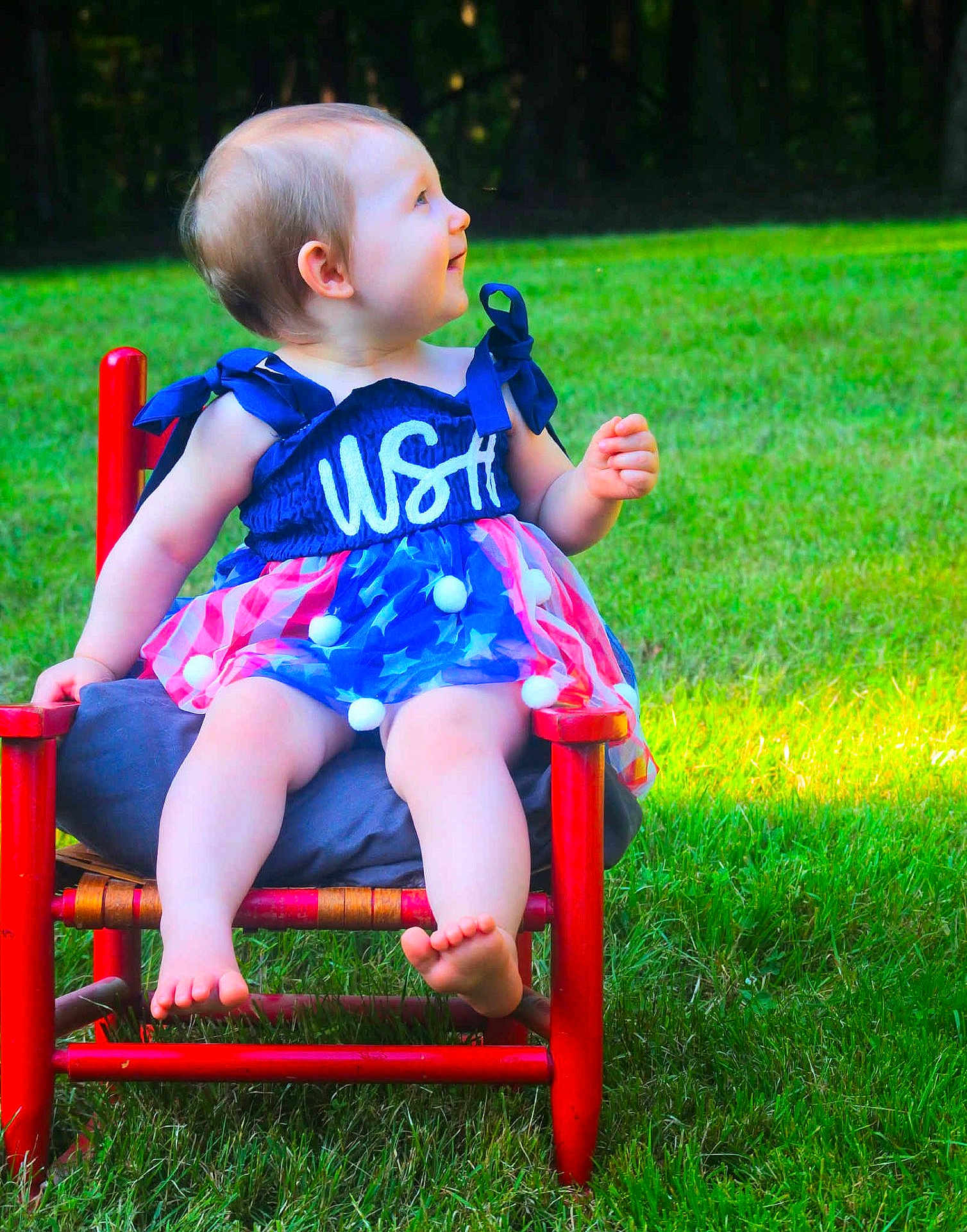 Oaklynn joined the competition — help win amazing prizes! baby, child, dress, red_chair, grass, outdoor, smile, barefoot, sitting, greenery, cute, summer, portrait, happy, nature, one_person, infant, sunlight, colorful, playful