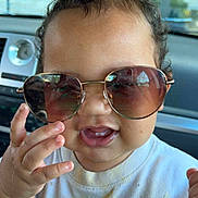 Maverick joined the competition — help win amazing prizes! car, child, close_up, clothing, curly_hair, cute, expression, face, hand, indoors, person, playful, reflection, seat, shirt, smiling, sunglasses, toddler, window, young
