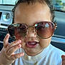 car, child, close_up, clothing, curly_hair, cute, expression, face, hand, indoors, person, playful, reflection, seat, shirt, smiling, sunglasses, toddler, window, young