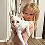 child, kitten, white_cat, indoor, wooden_floor, towels, doorway, curly_hair, bare_chest, purple_diaper, smiling, holding, pets, cute, young_child, curious, home, shoes, floor, portrait