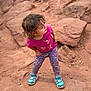 adventure, ballerina_print, casual_clothing, child, curious, daylight, dirt, floral_leggings, hands_on_hips, looking_away, nature, outdoor, pink_shirt, portrait, red_rocks, rocky, standing, toddler, turquoise_sneakers, young_child