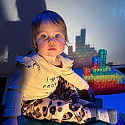 Aubrey is registered to the contest to win money with this photo: child, toddler, portrait, sitting, cross_legged, blue_lighting, colorful_lights, building_blocks, toy_blocks, playroom, leopard_print, ruffled_shirt, socks, brown_hair, blue_eyes, shadow, indoor, smiling, creative_play, photography