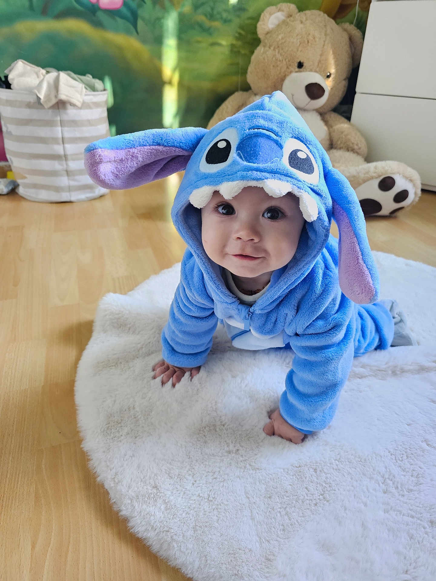 Neylan participe au concours pour gagner de l'argent avec cette photo : baby, child, costume, blue, crawling, floor, plush, toy, teddy_bear, home, indoor, cute, face, person, carpet, hood, smile, hand, foot, furniture