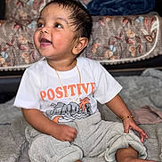 Ayansh joined the competition — help win amazing prizes! baby, child, toddler, sitting, smiling, happy, face, eyes, mouth, hair, shirt, clothing, gold_chain, bracelet, blanket, couch, patterned_background, indoors, feet, toes