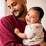 baby, father, parent, smile, laughing, hug, portrait, indoor, cozy, maroon_sweater, beard, short_hair, infant, holding, affectionate, happy, closeup, neutral_background, natural_light, casual_clothing