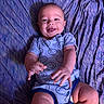 Colby is registered to the contest to win money with this photo: baby, infant, smiling, onesie, blue_clothing, happy, laying_down, blanket, texture, cute, child, person, skin, hand, legs, playful, tongue_out, indoors, portrait, young