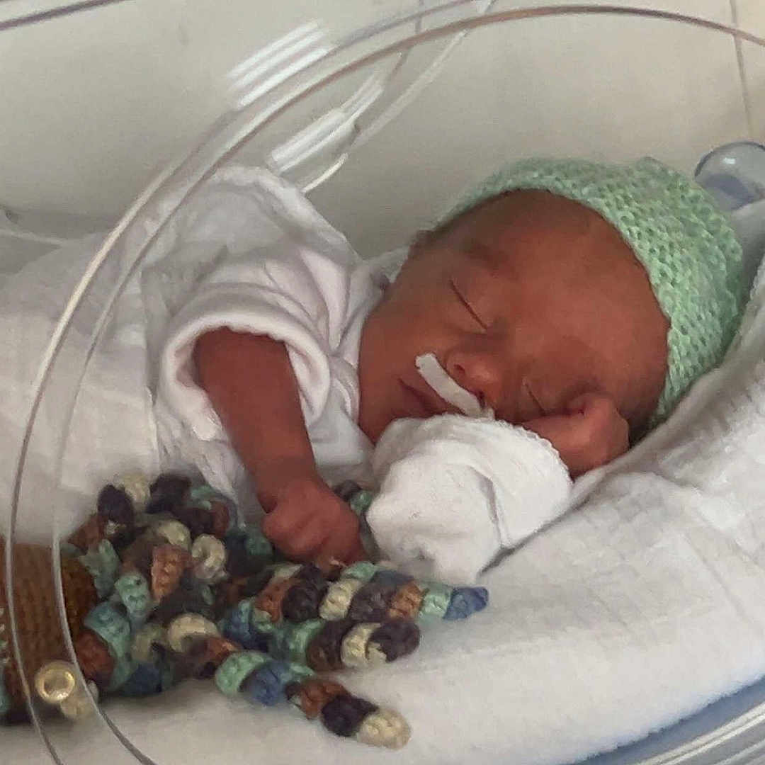 Arown participe au concours pour gagner de l'argent avec cette photo : architecture, baby, bed, blanket, building, clothing, crib, face, furniture, glove, hat, head, hospital, infantbed, newborn, person, photography, portrait, quilt, sleeping