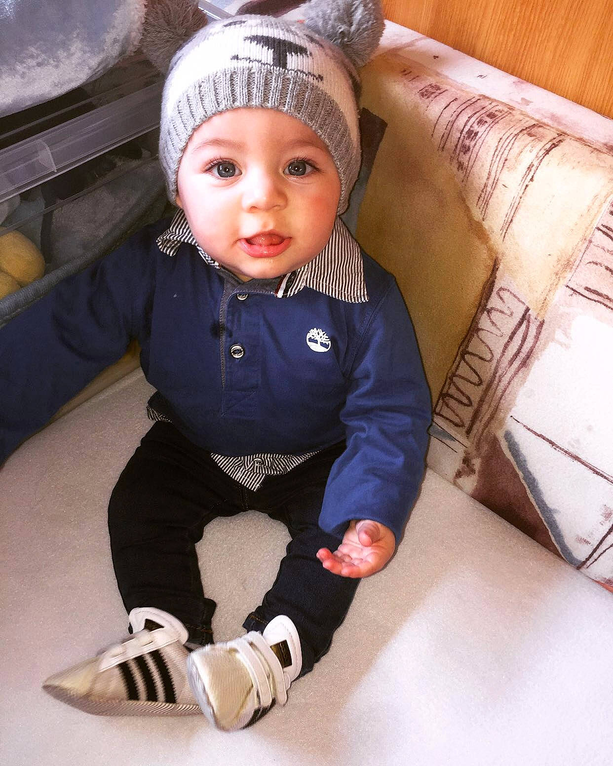 Yvann participe au concours pour gagner de l'argent avec cette photo : baby, baby_toddler_clothing, cap, collar, dress, eye, face, happy, hat, headgear, headwear, human_body, jacket, knee, leg, outerwear, person, personal_protective_equipment, sleeve, textile