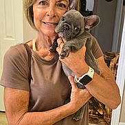 Diesel joined the competition — help win amazing prizes! woman, dog, puppy, french_bulldog, indoor, casual_clothing, smiling, holding, watch, short_hair, brown_shirt, blue_jeans, light_skin, pet, cute, home, doorway, floor_tiles, portrait, happy