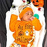 Ryan joined the competition — help win amazing prizes! baby, sleeping, infant, halloween, pumpkin, costume, orange_clothing, hat, onesie, stuffed_animal, ghost, spider, plush_toy, pacifier, beads, portrait, indoor, blanket, festive, seasonal