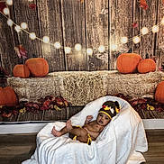 Ryan joined the competition — help win amazing prizes! baby, infant, child, portrait, costume, bee_costume, hat, blanket, wrapped, lying_down, autumn, pumpkins, hay_bale, fairy_lights, rustic, wooden_background, fall_leaves, indoor, cozy, photography