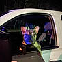 Stitch is registered to the contest to win money with this photo: dog, french_bulldog, car, window, night, animal, pet, vehicle, head, ears, paw, dark, trees, outdoor, lighting, colorful_lights, curious, looking_out, front_seat, shadow