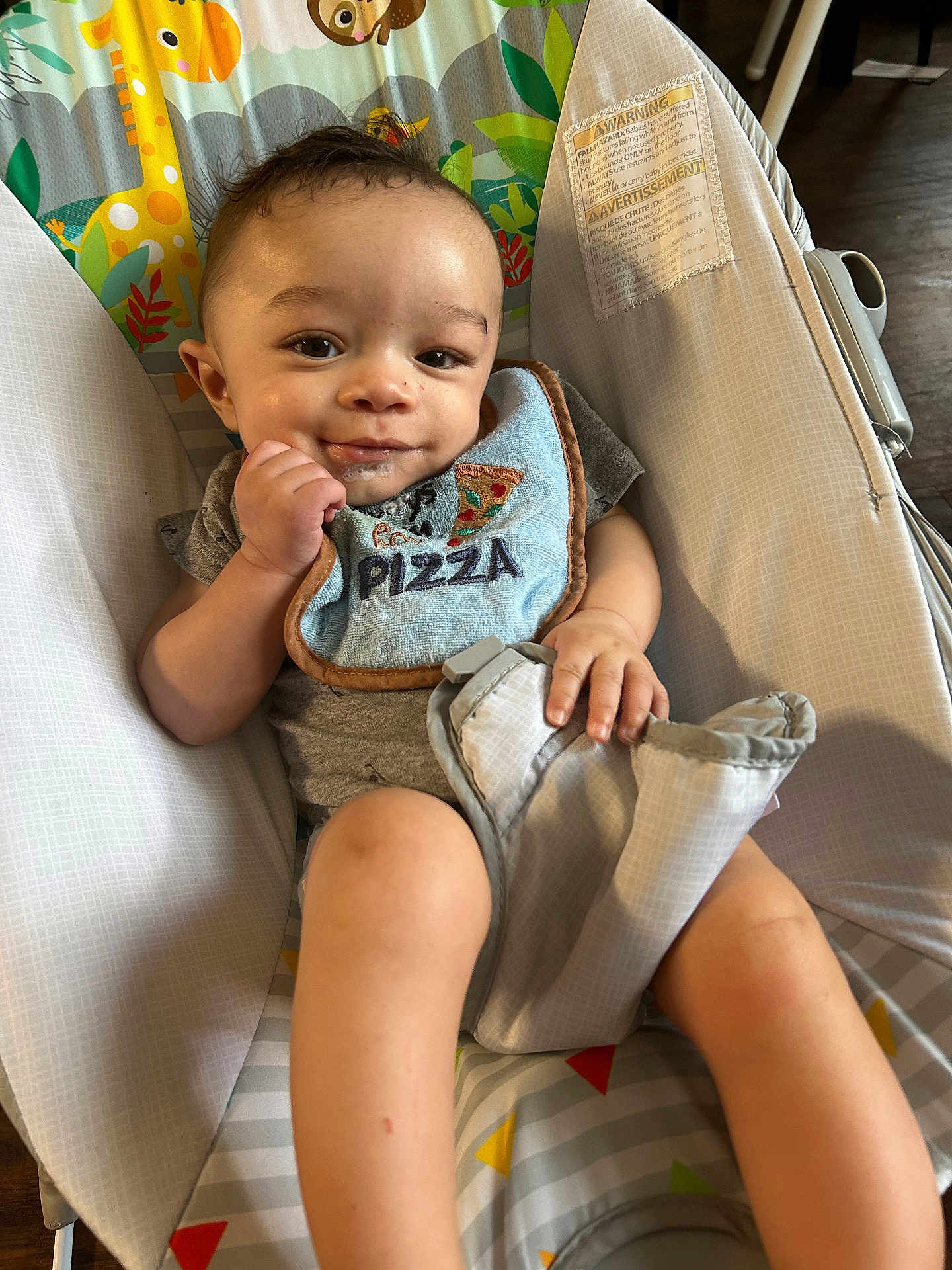 Zeke joined the competition — help win amazing prizes! baby, child, infant, bib, pizza, drool, baby_seat, smile, face, hand, legs, clothing, indoor, wood_floor, cute, young, portrait, comfort, playful, seat