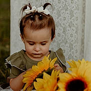 Stella joined the competition — help win amazing prizes! child, close_up, curious, cute, flower_bouquet, flowers, green_clothing, hair_bows, innocence, lace_curtain, nature, outdoor, pigtails, portrait, serious_expression, sitting, soft_lighting, sunflower, toddler, young_girl