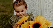Stella joined the competition — help win amazing prizes! baby, background, bows, child, clothing, cute, flowers, girl, grass, greenery, happy, innocent, lace, nature, outdoor, pigtails, portrait, smiling, sunflowers, toddler
