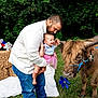 Stella joined the competition — help win amazing prizes! toddler, man, highland_cow, animal, grass, outdoor, hay_bale, american_flag, pinwheel, greenery, rope, horns, blue_rope, skirt, shirt, jeans, smile, nature, baby, hand