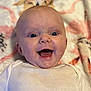 baby, blanket, child, closeup, cute, expression, face, happy, head, indoors, infant, lying_down, mouth_open, one_person, patterned_blanket, portrait, skin, smile, white_clothing, young_child