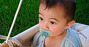 Tobias joined the competition — help win amazing prizes! baby, pacifier, swing, grass, outdoor, child, hand, wood, green, potted_plant, clothing, infant, cute, portrait, nature, seat, summer, play, face, garden