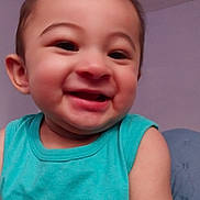 Tobias is registered to the contest to win money with this photo: baby, child, smiling, face, person, turquoise_shirt, sleeveless, happy, indoors, portrait, head, skin, cute, young_child, cheerful, seated, cozy, background, expression, closeup