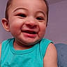 Tobias is registered to the contest to win money with this photo: baby, child, smiling, face, person, turquoise_shirt, sleeveless, happy, indoors, portrait, head, skin, cute, young_child, cheerful, seated, cozy, background, expression, closeup