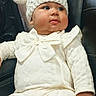 baby, baby_clothing, bow, bunny_hat, car, car_seat, child, cute, face, fashion, indoor, infant, knit_hat, leather_seat, photography, portrait, sitting, vehicle, white_outfit, wide_eyed