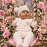 baby, child, face, fairy_tale, floral_decoration, flowers, garden, hands, infant, knit_hat, outdoor, photography, pink_flowers, pom_pom, portrait, roses, sitting, smiling, swing, white_outfit