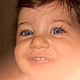 baby, child, face, blue_eyes, eyelashes, smile, teeth, closeup, portrait, skin, hair, forehead, nose, cheeks, toddler, candid, indoor, warm_tone, macro, cute