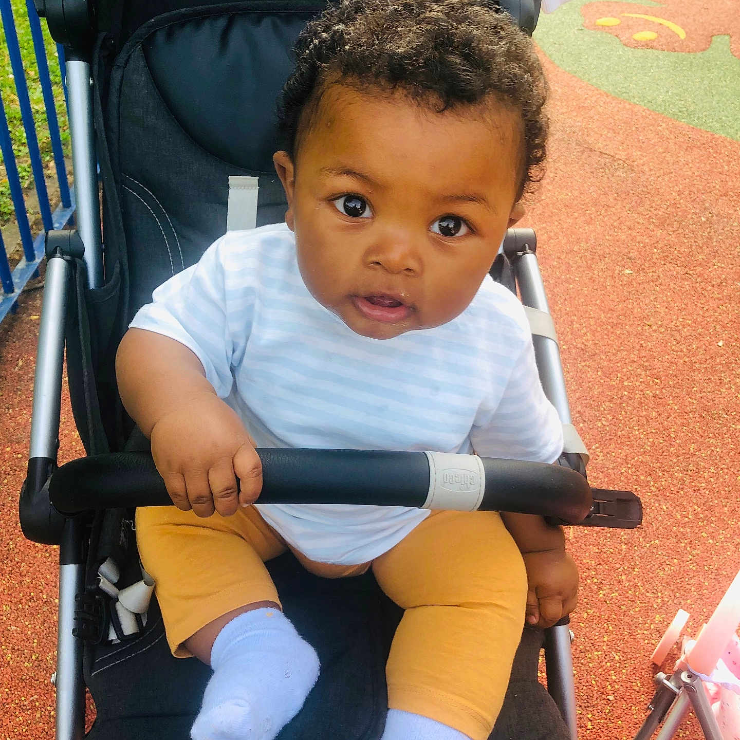 Mselam participe au concours pour gagner de l'argent avec cette photo : baby, child, clothing, curious, daytime, eyes, face, hair, hand, infant, outdoor, pants, person, play_area, playground, seat, shirt, socks, stroller, toy