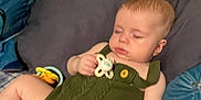 Anthony is registered to the contest to win money with this photo: baby, infant, sleeping, pacifier, green_outfit, romper, pillow, blanket, couch, indoor, closeup, face, hand, leg, toy, button, soft_fabric, naptime, casual_photo, blurred