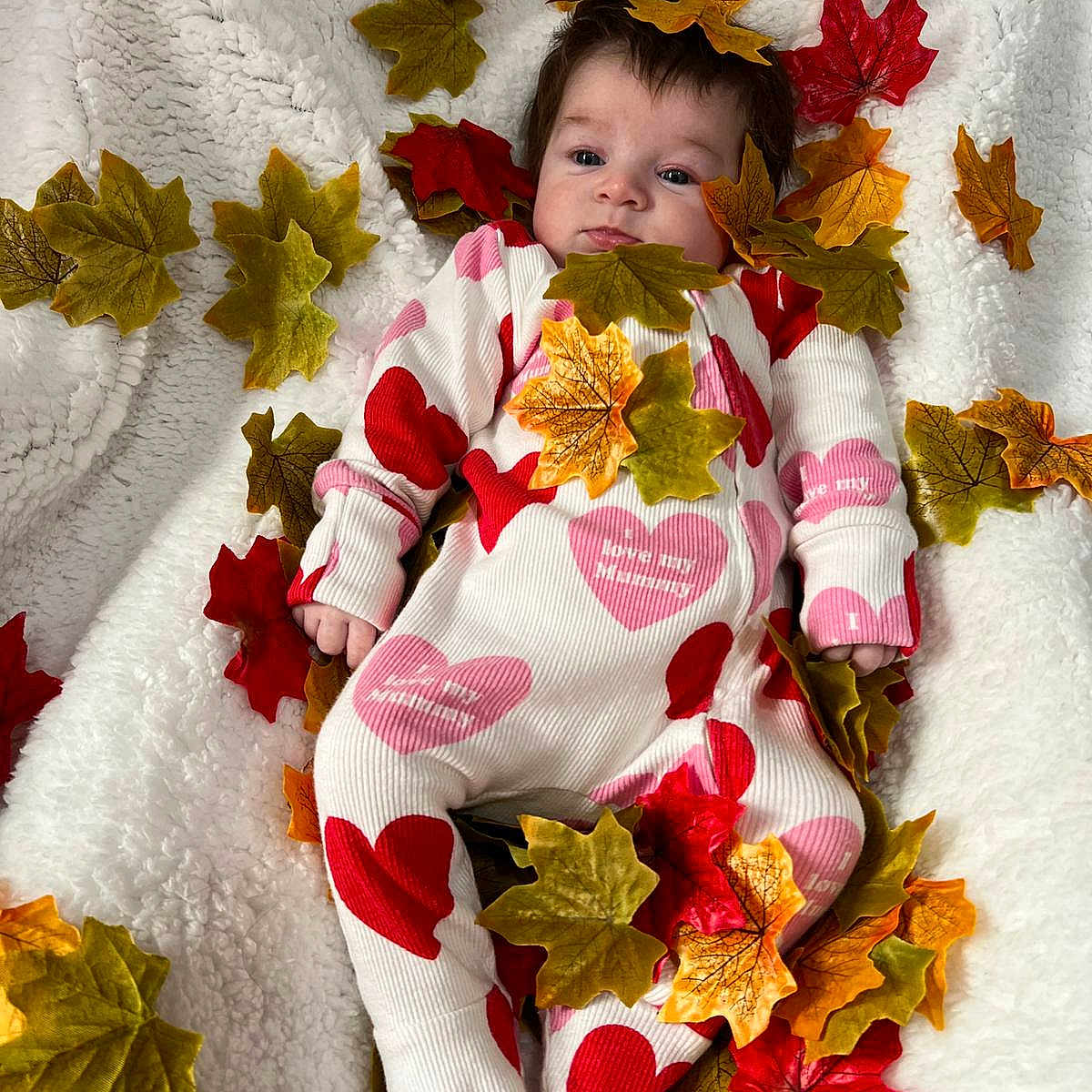Alexa-Rae joined the competition — help win amazing prizes! autumn_leaves, baby, blanket, child, cozy, cute, face, fall, heart_pattern, infant, lying_down, onesie, orange, person, pink, red, sleepwear, soft_texture, white, yellow