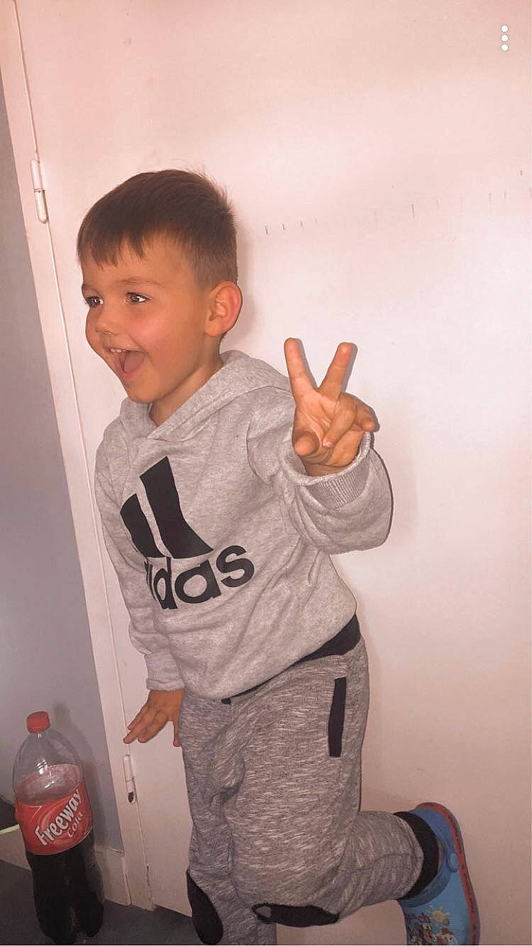 Matéane a rejoint le concours — aidez-le/la à gagner de superbes lots ! carbonated_soft_drinks, child, drink, elbow, fun, gesture, happy, long_sleeved_t_shirt, pattern, person, plastic_bottle, room, sleeve, smile, standing, t_shirt, thumb, toddler, top, waist