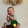Clayton is registered to the contest to win money with this photo: baby, child, smiling, sitting, toy, stuffed_animal, duck, plush, clothing, striped_shirt, barefoot, milestone, garland, tassels, celebration, indoor, portrait, happy, cute, studio