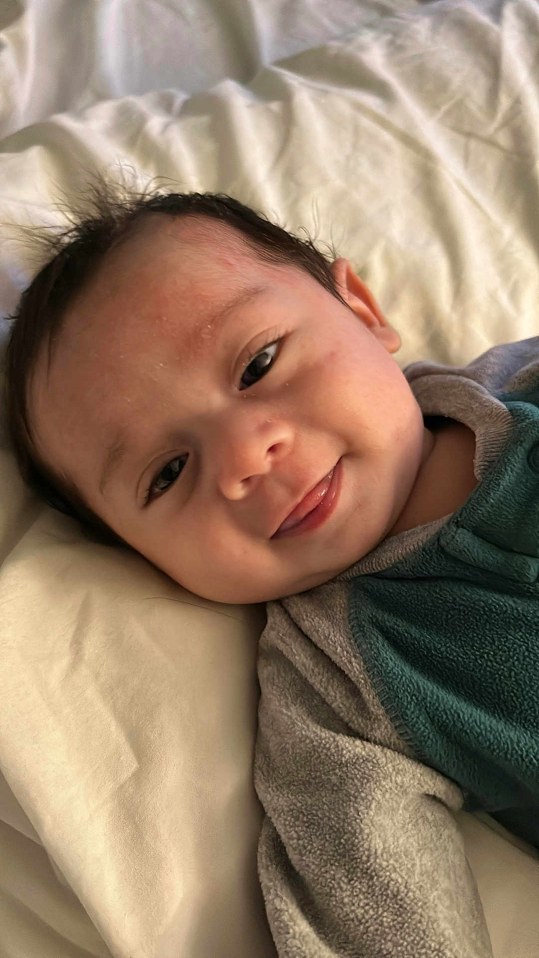 Noah Smith Pérez is registered to the contest to win money with this photo: baby, smiling, face, infant, child, blanket, cozy, clothing, cute, portrait, lying_down, young_child, head, happy, skin, eyelashes, hair, indoors, soft_texture, closeup