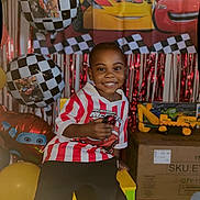 Cymbian joined the competition — help win amazing prizes! child, smiling, birthday, balloons, toy_car, red_white_striped_shirt, black_pants, checkered_pattern, decorations, party, indoor, celebration, young_boy, colorful, cardboard_boxes, yellow_chair, happy, portrait, festive, background