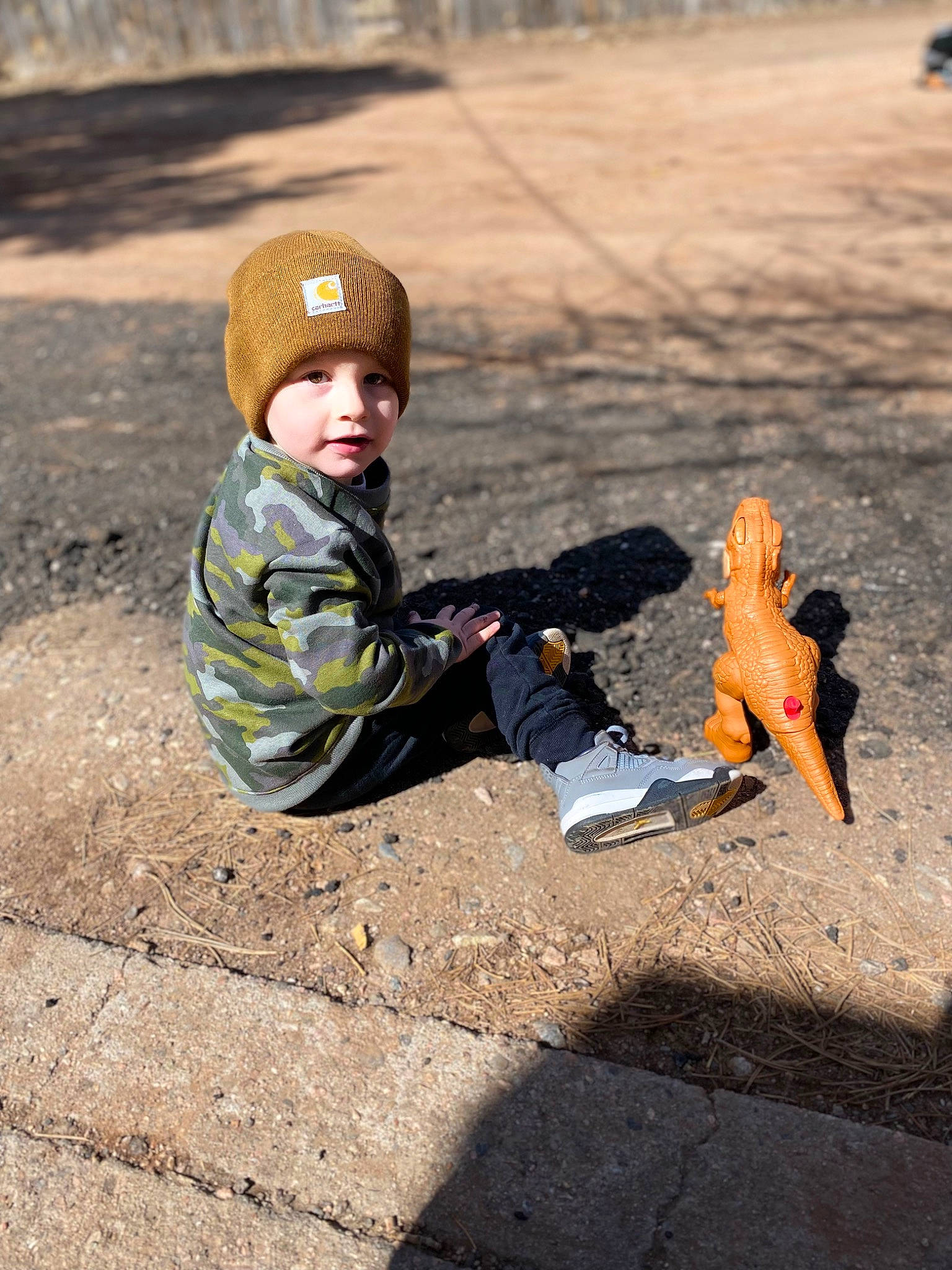 Gerald is registered to the contest to win money with this photo: asphalt, boot, cap, fun, grass, happy, headwear, jacket, landscape, leg, leisure, people, people_in_nature, person, public_space, recreation, sand, shoe, sitting, sneakers