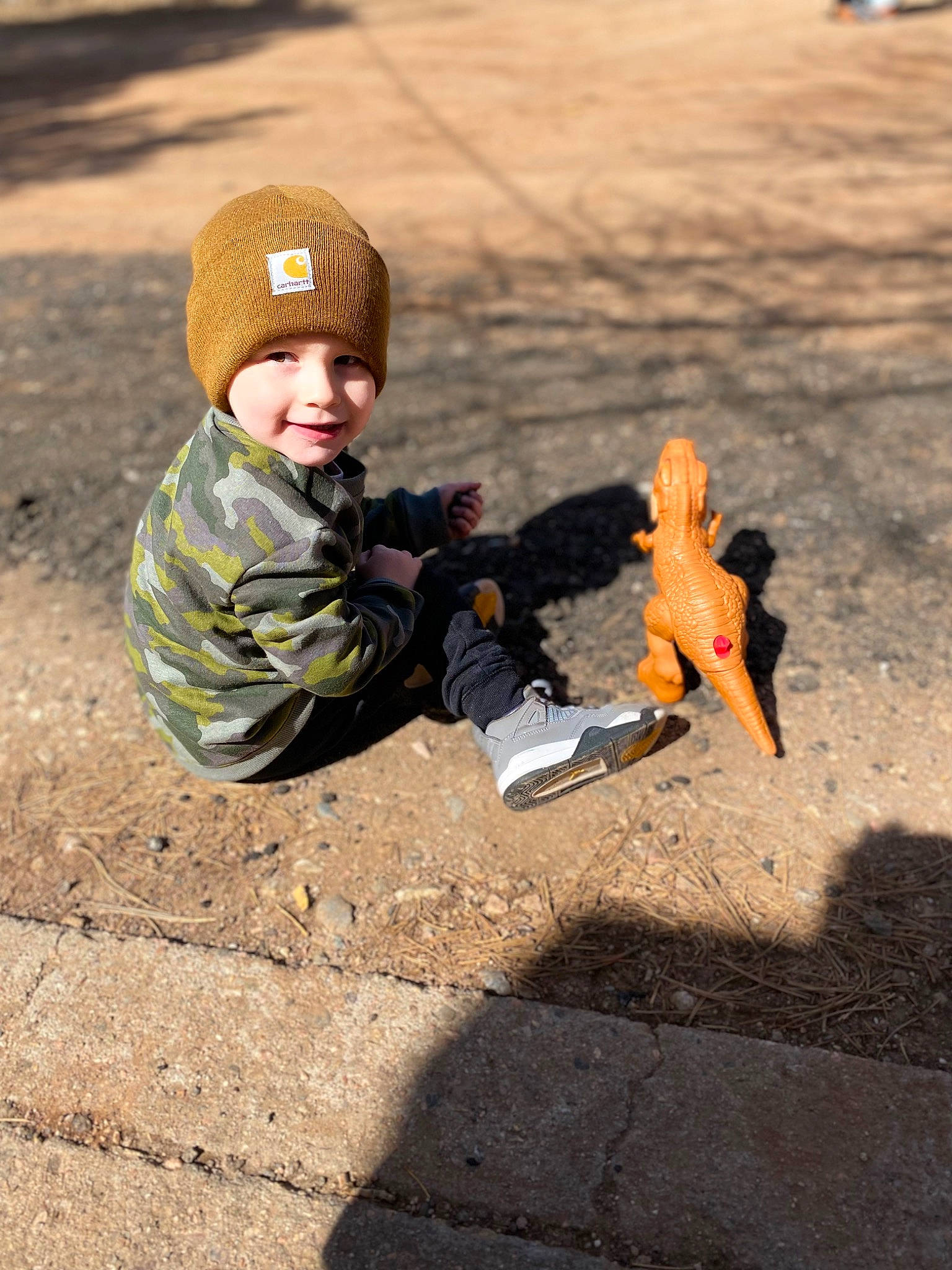 Gerald is registered to the contest to win money with this photo: asphalt, baby, cap, city, fun, grass, headwear, jacket, joy, landscape, leaf, leisure, orange, people_in_nature, person, play, recreation, road_surface, sand, sitting