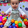 baby, child, ball_pit, colorful_balls, romper, polka_dot, playtime, outdoor, happy, cute, infant, feet, toys, smiling, sitting, bright_colors, fun, person, portrait, young_child