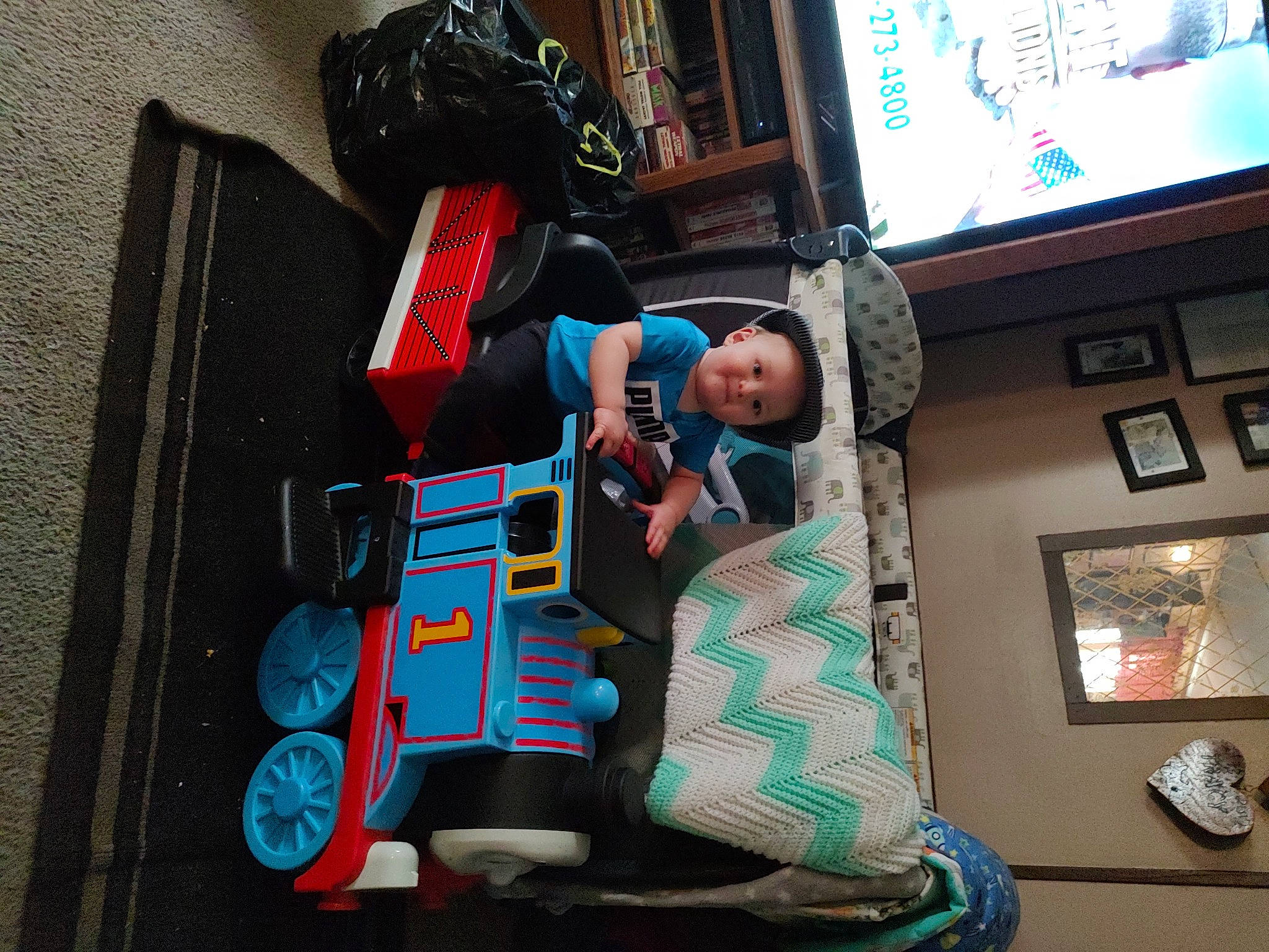 Thomas is registered to the contest to win money with this photo: baby_products, child, costume, display_device, electronic_device, fictional_character, fun, hat, leisure, machine, person, picture_frame, recreation, room, sitting, t_shirt, television, tire, toddler, travel