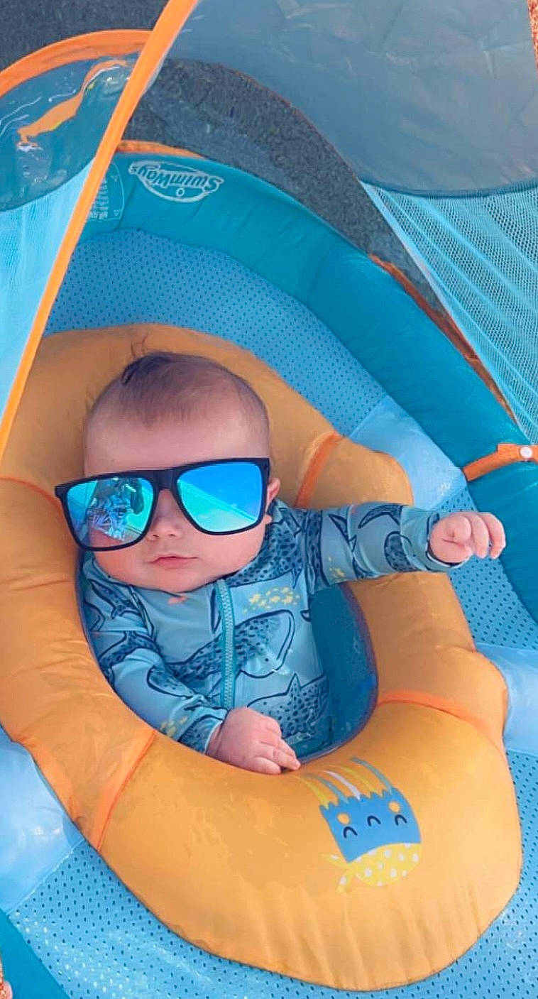 William is registered to the contest to win money with this photo: azure, baby, baby_toddler_clothing, child, comfort, electric_blue, eyewear, fun, goggles, hat, leisure, person, personal_protective_equipment, play, recreation, sitting, smile, sunglasses, thumb, toddler