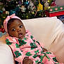 Christina is registered to the contest to win money with this photo: baby, child, infant, christmas_tree, holiday, pajamas, pink_clothing, festive, gift_boxes, decorations, ornaments, soft_blanket, indoor, smiling, cute, person, headband, holiday_lights, cozy, celebration