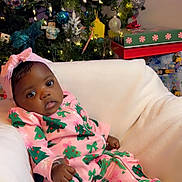 Christina is registered to the contest to win money with this photo: baby, infant, child, christmas_tree, holiday, pajamas, pink_clothing, headband, gift_boxes, ornaments, decorations, lights, festive, cozy, chair, portrait, indoors, cute, seasonal, celebration