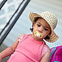 toddler, child, pacifier, hat, pink_top, backpack, outdoor, portrait, person, curly_hair, expression, sitting, railing, casual, summer, young_child, fashion, closeup, headwear, daylight