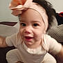 baby, headband, bow, infant, child, smile, face, person, clothing, sitting, indoors, cute, apparel, baby_outfit, happy, skin, hair, young_child, soft_furniture, home