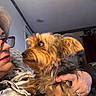 Bridgette is registered to the contest to win money with this photo: dog, woman, glasses, indoor, affection, pet, love, holding, scruffy_dog, face, hand, casual_clothing, curtain, home, couch, portrait, closeup, light, expression, interaction