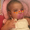 Maylynn is registered to the contest to win money with this photo: baby, infant, child, sleeping, pacifier, portrait, close_up, pink_blanket, white_dress, floral_detail, autumn_leaves, face_stickers, lying_down, cozy, indoor, soft_lighting, bed, blanket, baby_clothing, photograph